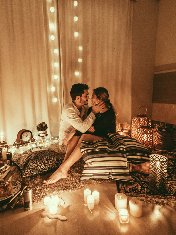 Couple sitting on bed surrounded by candles