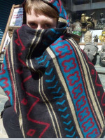 Model wrapped in an ethnic Nepalese shawl featuring bold tribal motifs, geometric bands and contrasting patterned borders.