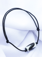 Handcrafted Tibetan Dzi bead bracelet and necklace set with black adjustable cords, displayed on a white fabric background.