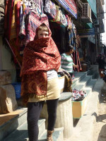Woman wearing a brushed cotton and acrylic Indian shawl with an intricate floral pattern, decorative border and fringed edges.