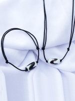 Handcrafted Tibetan Dzi bead bracelet and necklace set with black adjustable cords, displayed on a white fabric background.